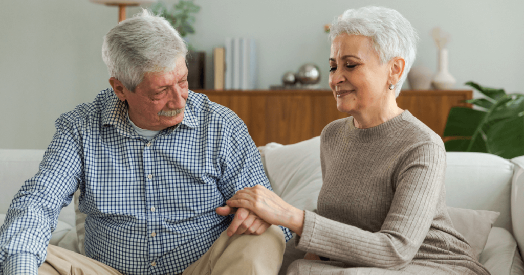 Older couple sitting down on the couch speaking about when is it time for memory care